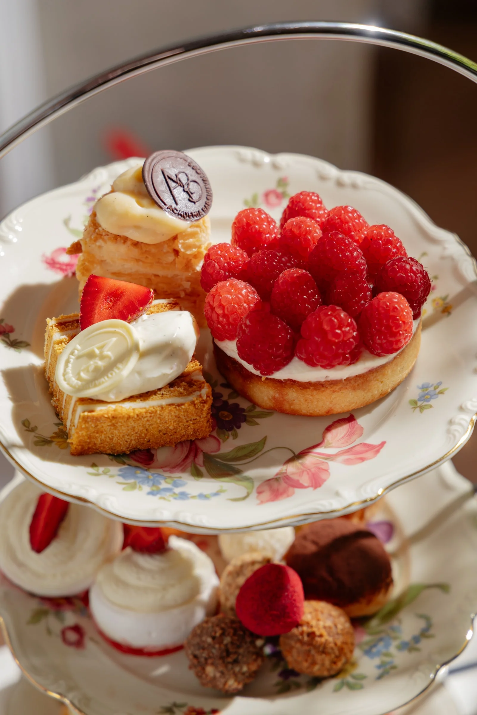 Raspberry tartlet and desserts with the ACADEMIA chocolate emblem on a porcelain tier plate
